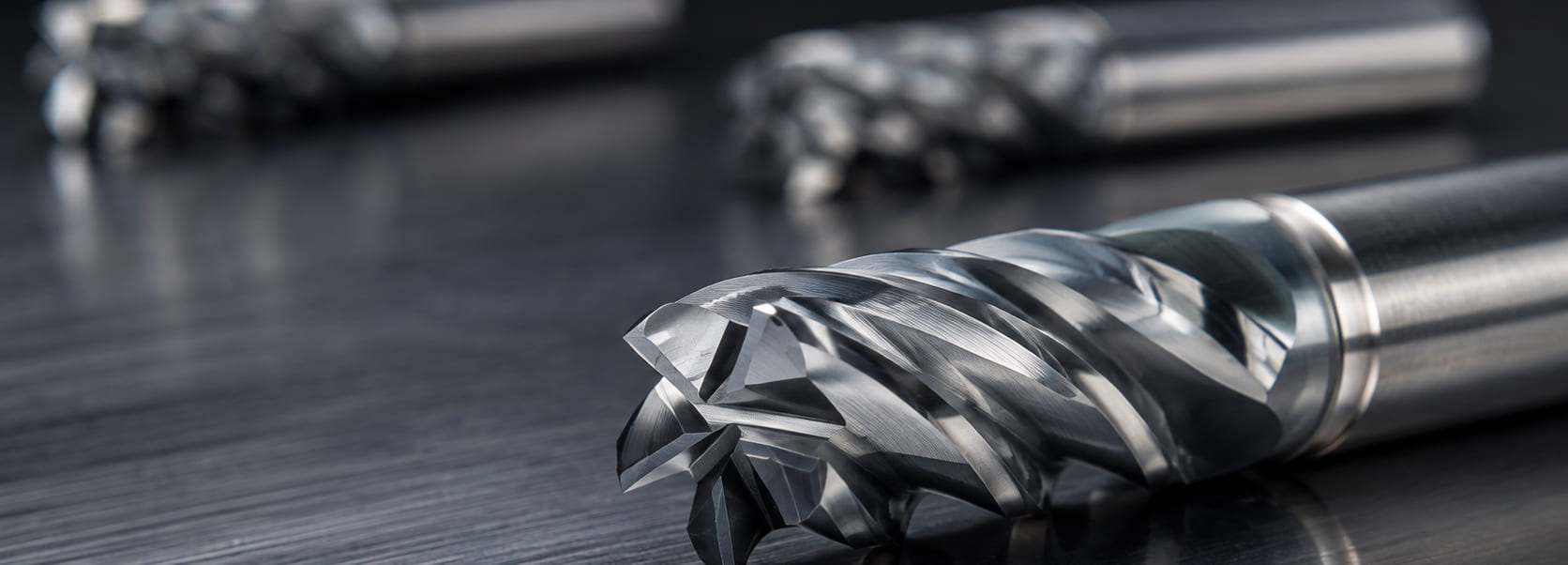 EUROCUTPRECISION Z5 Series solid carbide end mill, cutting geometry in focus, with two further tools behind on a dark machined ground